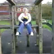 A girl pees while sitting up high on some playground equipment in a schoolyard in this very brief, low resolution video clip.